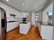 Open kitchen with wooden floors, center island with sink, white cabinetry, and stainless steel refrigerator at 11365 Donnington Dr, Duluth, GA 30097