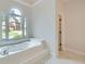 Elegant bathroom boasting a soaking tub with a view of the lawn at 140 Grosvenor Pl, Atlanta, GA 30328