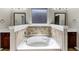Bright bathroom featuring a soaking tub with tile surround, dual mirrors and sinks at 3777 Shady Maple Dr, Lithonia, GA 30038