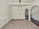 Open-concept dining room with wainscoting, tray ceiling, and view of the kitchen and arched doorway at 3777 Shady Maple Dr, Lithonia, GA 30038
