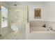 Bright bathroom featuring a frameless shower enclosure, soaking tub with tile surround, and a decorative mirror at 411 Johnson Ct, Alpharetta, GA 30009