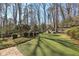 Spacious backyard featuring artificial turf, mature trees, landscaping and a wooden playset at 3902 Sheldon Ne Dr, Atlanta, GA 30342