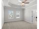 Large, carpeted bedroom with a decorative tray ceiling and an open door to the bathroom at 175 Basil St, Cumming, GA 30040