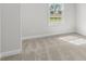A bedroom with neutral carpet, white trim, and a window providing natural light at 175 Basil St, Cumming, GA 30040