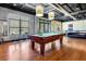 This game room features a pool table, exposed ductwork, ample seating, natural light, and hardwood flooring at 5300 Peachtree Rd # 1311, Atlanta, GA 30341