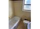 Bathroom features a white bathtub, toilet, and yellow tile with dark accents at 542 Sugar Hill Nw Dr, Marietta, GA 30060