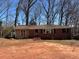 Charming single-story house featuring a brick exterior, a large window, and cozy entrance, all surrounded by mature trees at 542 Sugar Hill Nw Dr, Marietta, GA 30060