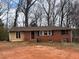 Classic single-story house featuring a brick exterior, large window, and cozy entrance, all surrounded by mature trees at 542 Sugar Hill Nw Dr, Marietta, GA 30060