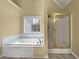 A bathroom features a jacuzzi tub with tile surround and a separate shower stall with a glass door at 439 Emerald Trce, Jonesboro, GA 30236