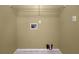 An empty laundry room showcases utility connections and a wire shelf for organizing laundry supplies at 439 Emerald Trce, Jonesboro, GA 30236