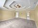 An expansive main bedroom has neutral-toned walls, plush carpet flooring, and a tray ceiling with a ceiling fan at 439 Emerald Trce, Jonesboro, GA 30236