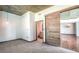 Bright room with gray carpet, concrete ceiling, and a view into the bathroom through a sliding wood door at 860 Peachtree Ne St # 917, Atlanta, GA 30308