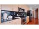 Modern kitchen featuring stainless steel appliances, wood cabinets, and black tile backsplash at 860 Peachtree Ne St # 917, Atlanta, GA 30308