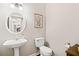Cozy powder room with a pedestal sink, toilet, and decorative mirror at 7104 Big Woods Dr, Woodstock, GA 30189