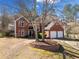 Inviting two-story brick home with a two-car garage, complemented by mature trees and landscaped features at 7104 Big Woods Dr, Woodstock, GA 30189