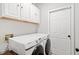 Well-lit laundry room with washer, dryer, and overhead storage cabinets at 7104 Big Woods Dr, Woodstock, GA 30189
