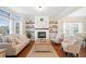 Cozy living room with a fireplace, wood floors, and plenty of natural light from large windows at 7104 Big Woods Dr, Woodstock, GA 30189