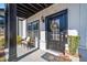 A closer view of the townhome front door with black trim and covered porch, including a wicker chair at 1053 Knoxboro Ln, Woodstock, GA 30188