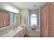 A well-lit bathroom featuring a vanity, large mirror, shower, and jacuzzi at 1023 Spruce Creek Ln, Lawrenceville, GA 30045