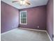 Bedroom with neutral carpet, purple accent wall, and natural light at 750 Beckenham Walk Dr, Dacula, GA 30019