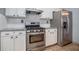Close-up of modern kitchen featuring stainless steel appliances, white cabinetry, granite countertops, and modern range hood at 750 Beckenham Walk Dr, Dacula, GA 30019