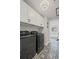 Laundry room with upper cabinets, black and white decorative flooring, and a black front-load washer and dryer at 330 Peninsula Pt, Canton, GA 30115