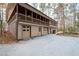 Rear exterior view showcasing attached garages, a gravel driveway, and the home's private, wooded setting at 244 Sherbrook Nw Ct, Marietta, GA 30064