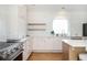 Charming kitchen boasts white cabinets, wooden shelving, stainless steel appliances, and a large arched window at 4349 Highborne Ne Dr, Marietta, GA 30066