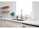 Close-up of kitchen sink area featuring white countertop, stainless steel sink, arched window, and wooden shelves at 4349 Highborne Ne Dr, Marietta, GA 30066