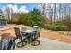 Backyard with patio including a table and four chairs, along with landscaping, bushes and a wooded area at 505 Appalachian Woods Dr, Canton, GA 30114