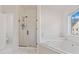 Bright bathroom boasts a glass shower, soaking tub, and a window with backyard views at 3130 Caney Creek Ln, Cumming, GA 30041