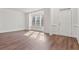 Bright room featuring hardwood floors, three windows bringing in light, white walls, and a white front door at 3130 Caney Creek Ln, Cumming, GA 30041
