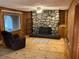 Cozy living room featuring wood walls, a striking stone fireplace, and natural light at 8395 Atlanta Newnan Rd, Chattahoochee Hills, GA 30268