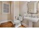 Cozy powder room with pedestal sink, decorative mirror, and plantation shutters at 13029 Dartmore Ave, Alpharetta, GA 30005