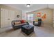Bonus room featuring a comfortable sofa, ottoman, modern artwork, and window for natural light at 13029 Dartmore Ave, Alpharetta, GA 30005