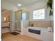 Bright bathroom with a glass-enclosed shower, bathtub, and decorative window at 2392 Ivy Mountain Dr, Snellville, GA 30078
