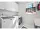 Laundry room with white washer and dryer, overhead cabinets and bright light at 2431 Valhalla Ne Dr, Atlanta, GA 30345