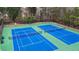 Aerial shot of two blue and green tennis courts surrounded by a black fence and trees at 4831 Lake Park Ter, Acworth, GA 30101