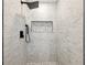 Modern shower with white tiled walls, black fixtures and a built-in niche with pebble accents at 1355 Lockwood Sw Dr, Atlanta, GA 30311