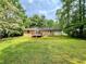 Spacious backyard featuring a small deck, lush greenery, and mature trees providing ample shade at 371 Landers Sw Dr, Mableton, GA 30126