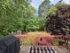 A deck with a table and chairs overlooks a wooded backyard, ideal for outdoor relaxation at 4184 Wyndham Park Way, Buford, GA 30519