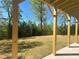 View from covered patio with timber posts showing a yard with a treeline in the distance at 630 Gilles Ln, Cumming, GA 30041