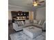 Bright living room showcasing a stylish gray sectional sofa, a ceiling fan, and adjacent view to the kitchen at 3671 Casual Ridge Way, Loganville, GA 30052