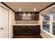 Elegant wet bar featuring custom cabinetry, a mosaic backsplash, and granite countertops at 1837 Haven Park Se Cir, Smyrna, GA 30080