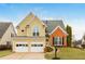 Charming yellow two-story home featuring an attached two car garage and brick accent details at 2038 Drogheda Ln, Marietta, GA 30066