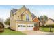 Charming two-story home in yellow featuring a two car garage, brick accents, and manicured lawn at 2038 Drogheda Ln, Marietta, GA 30066