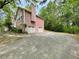 Side exterior of home featuring a two-car garage, ample parking space, and mature landscaping at 610 Coolsprings Ln, Woodstock, GA 30188