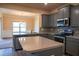 Modern kitchen with gray cabinets, granite countertops, and stainless steel appliances adjacent to a dining area at 11978 Quail Rd, Hampton, GA 30228
