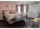 This bedroom is playfully decorated with pink walls, a cozy bed, a chandelier, and hardwood floors at 3302 Willow Meadow Ln, Douglasville, GA 30135