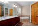 Bathroom with double vanity, soaking tub, tiled floors, and natural wood door at 281 Chilhoe Dr, Canton, GA 30115